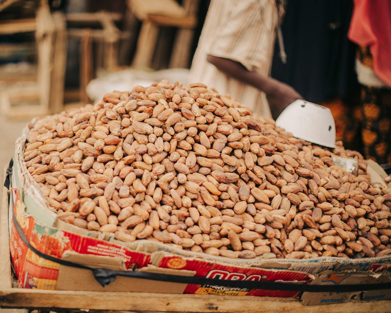 Large pile of cocoa beans on a vendor stand in a market, ready for trade.